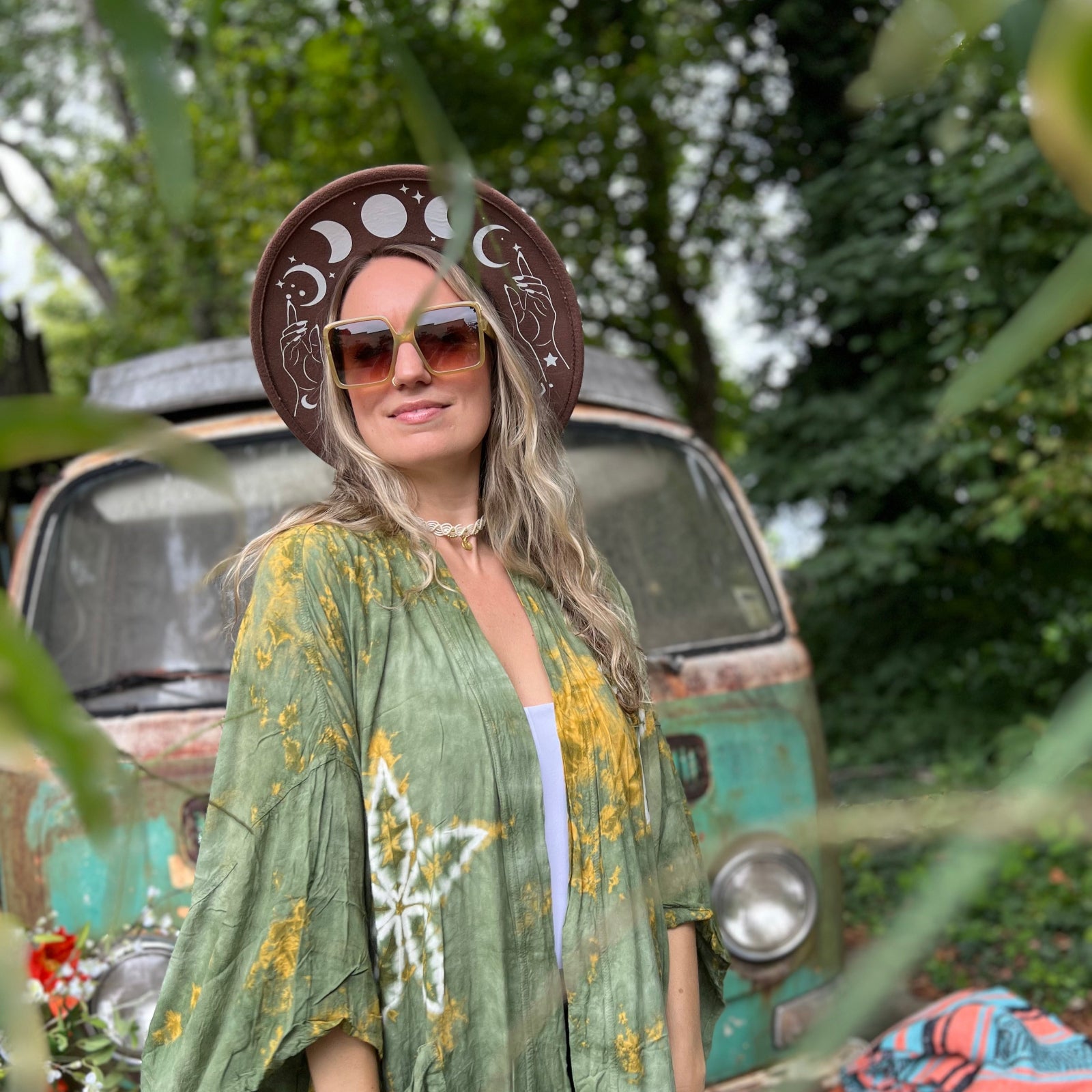 A woman wearing the olive Kelso 70s Sunglasses with a brown hat and green. kimono.