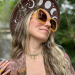 A woman wearing the marigold Sofia Sunglasses with a tie-dye kimono.