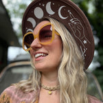 A woman wearing the marigold Sofia Sunglasses with a tie-dye kimono.