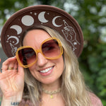 A woman wearing the marigold Sofia Sunglasses with a tie-dye kimono.