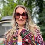 A woman wearing the turquoise Sofia Sunglasses with a colorful jacket.