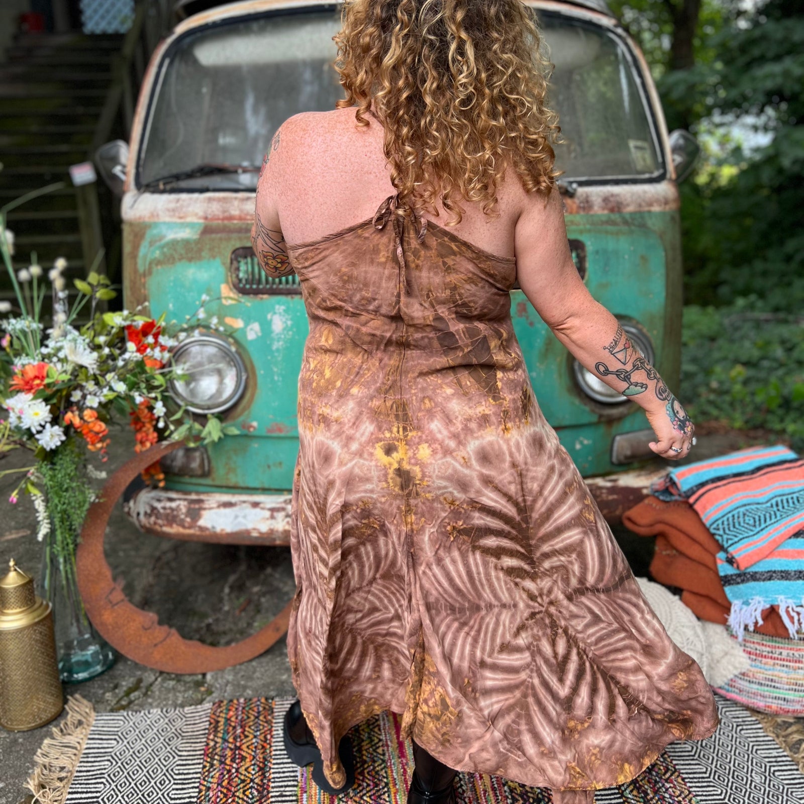 A woman wearing the moondance mauve gold Hippie Boho Maxi Flowy Tie Dye Dress in front of a vintage Volkswagen Bus.