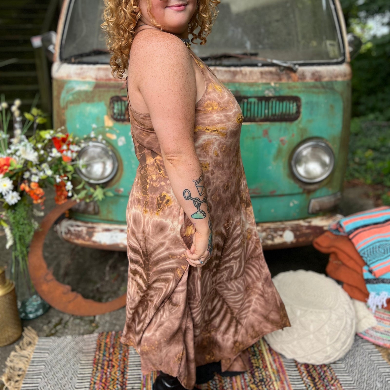 A woman wearing the moondance mauve gold Hippie Boho Maxi Flowy Tie Dye Dress in front of a vintage Volkswagen Bus.