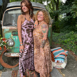 Two women wearing the moondance mauve gold Hippie Boho Maxi Flowy Tie Dye Dress in front of a vintage Volkswagen Bus.