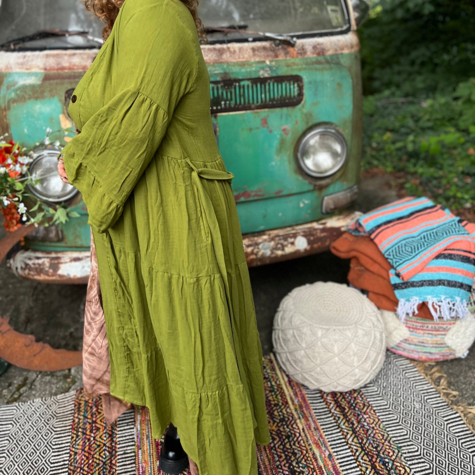 A woman wearing the golden Cyprus green Organic Tiered Maxi Kimono Wrap Dress in front of a vintage Volkswagen bus.
