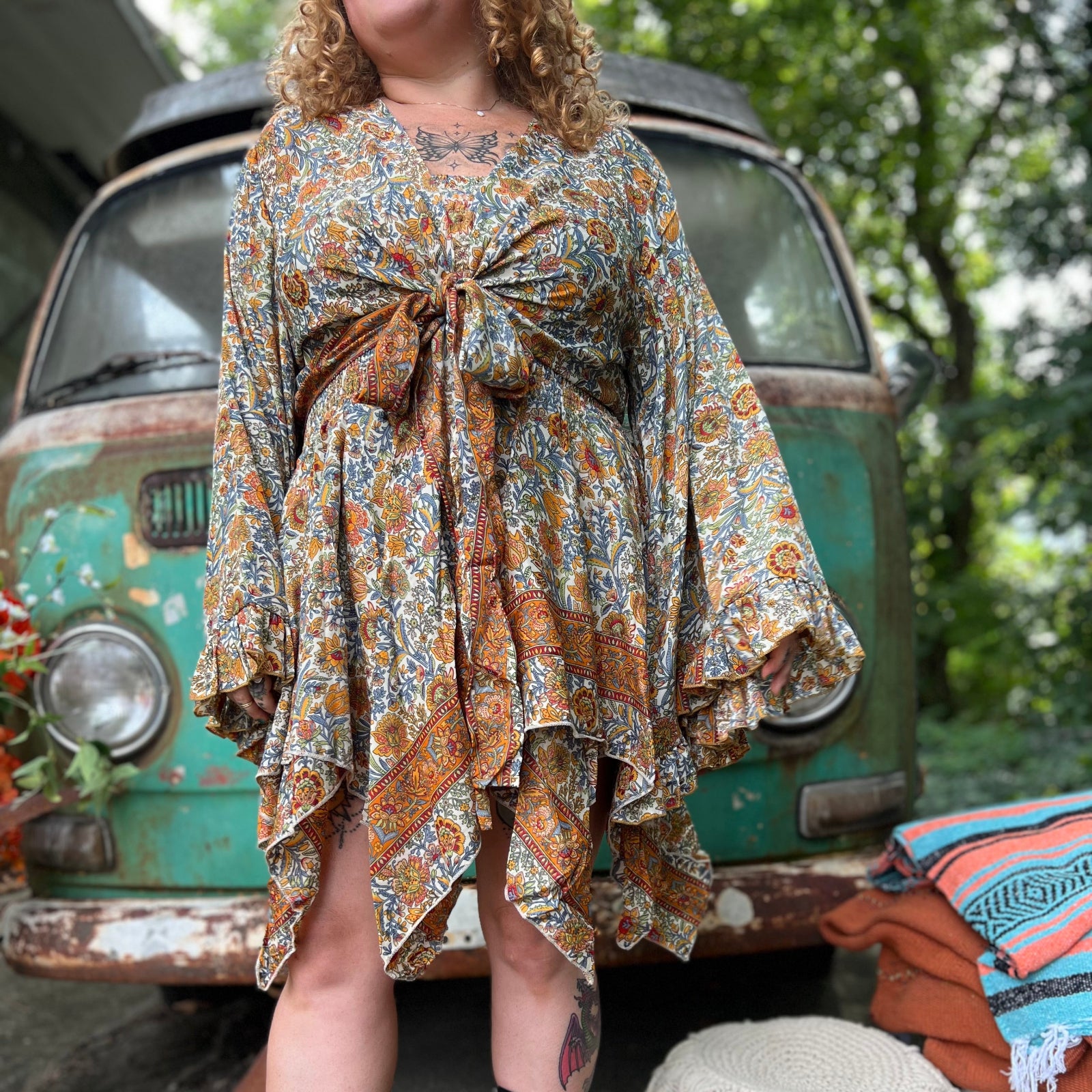 A woman wearing the orange and cream Hippie Bohemian Fairy Dress with Elastic Fairy Skirt in front of a vintage Volkswagen bus.