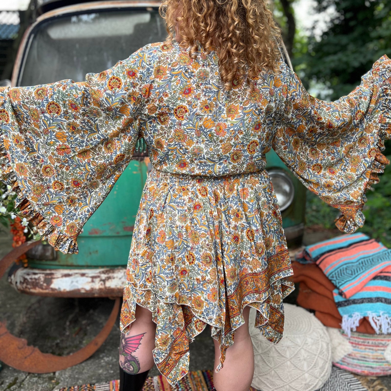 A woman wearing the orange and cream Hippie Bohemian Fairy Dress with Elastic Fairy Skirt in front of a vintage Volkswagen bus.