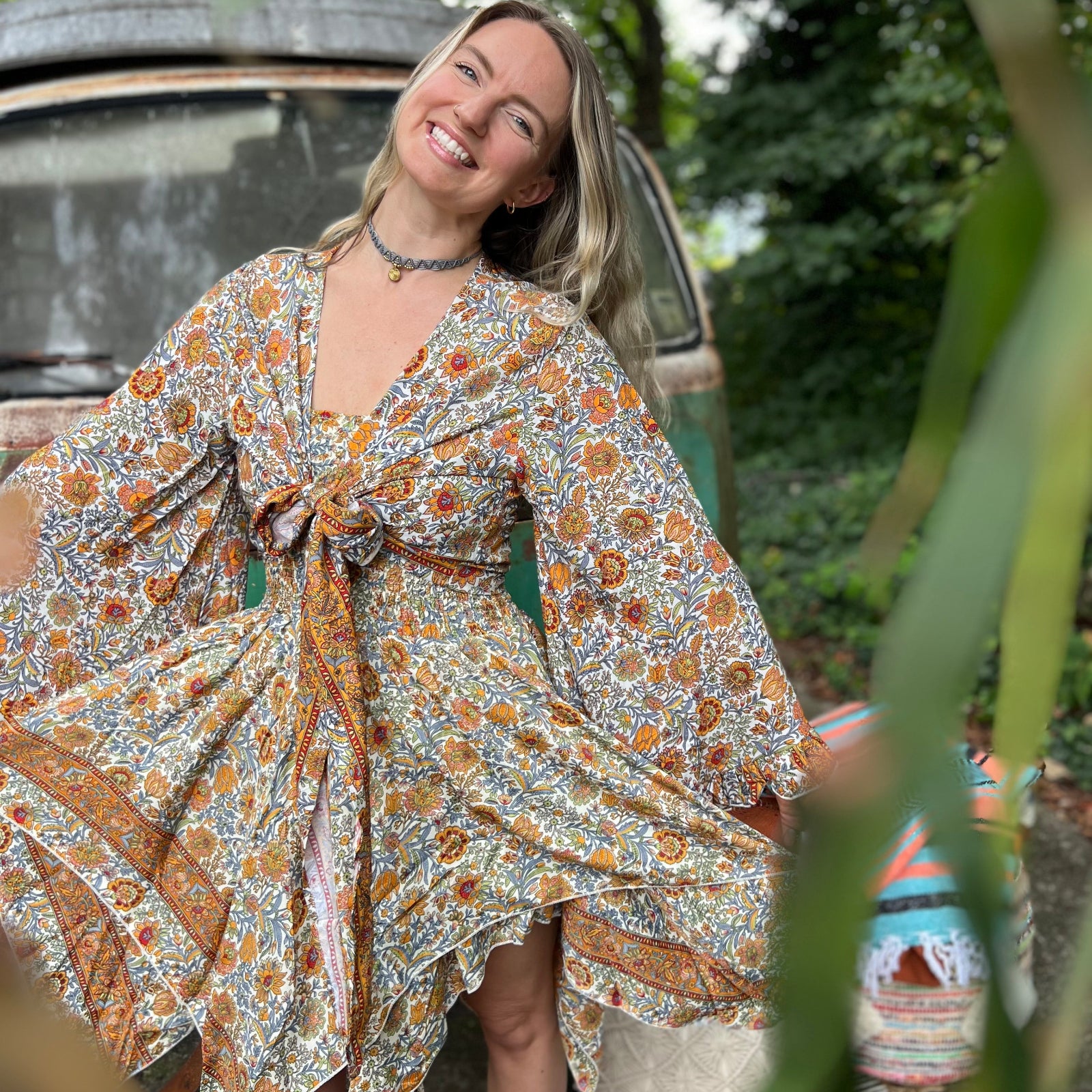 A woman wearing the orange and cream Hippie Bohemian Fairy Dress with Elastic Fairy Skirt in front of a vintage Volkswagen bus.