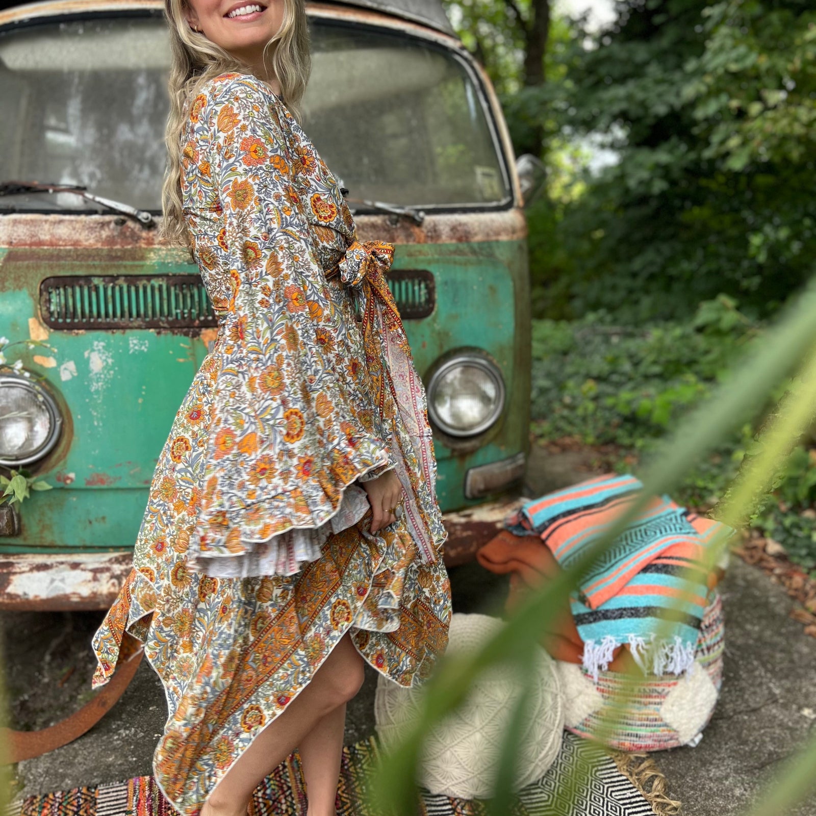 A woman wearing the orange and cream Hippie Bohemian Fairy Dress with Elastic Fairy Skirt in front of a vintage Volkswagen bus.
