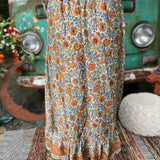 Someone wearing the orange & cream Hippie Floral Cinch Maxi Ruffle Skirt in front of a Volkswagen bus.