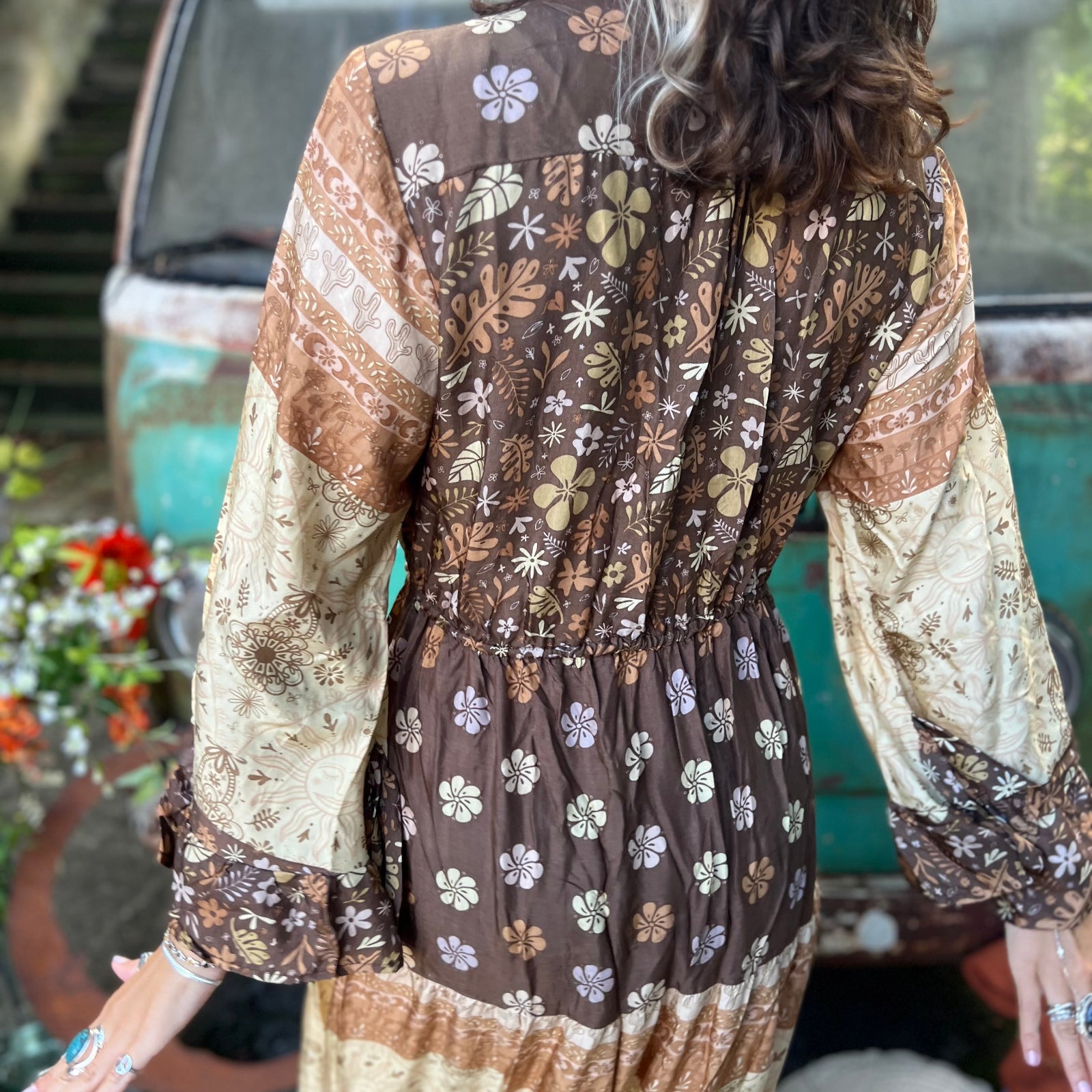A woman wearing the Earthy Solstice Boho Bell Sleeve Maxi Dress in front of a vintage Volkswagen bus.