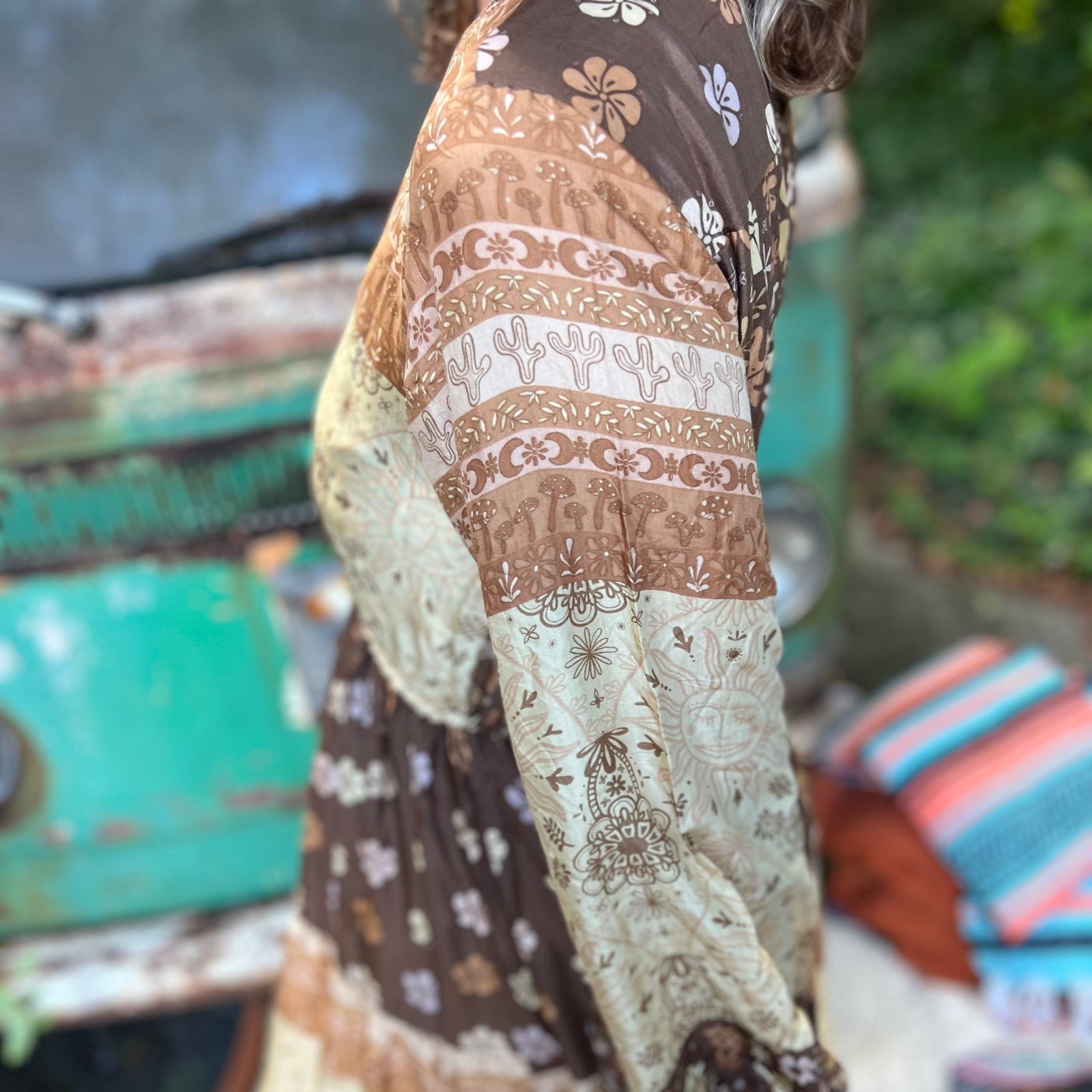 A woman wearing the Earthy Solstice Boho Bell Sleeve Maxi Dress in front of a vintage Volkswagen bus.