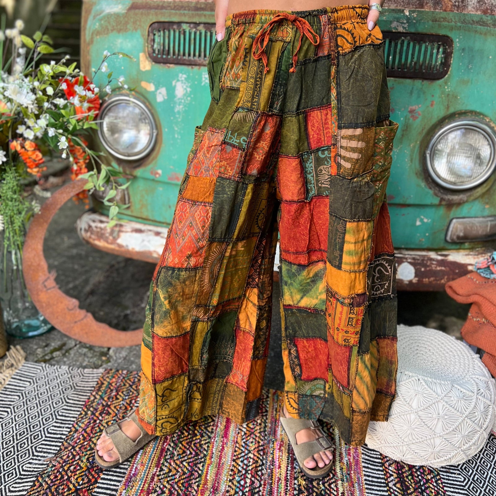 A woman wearing the Bohemian Patchwork Flare Wide Leg Pants in front of a vintage Volkswagen bus.