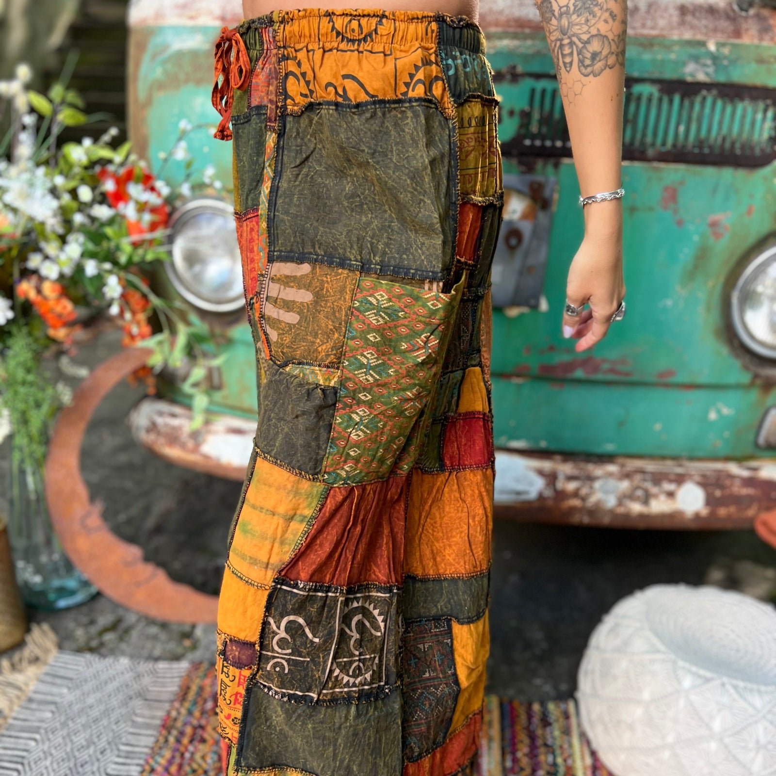A woman wearing the Bohemian Patchwork Flare Wide Leg Pants in front of a vintage Volkswagen bus.