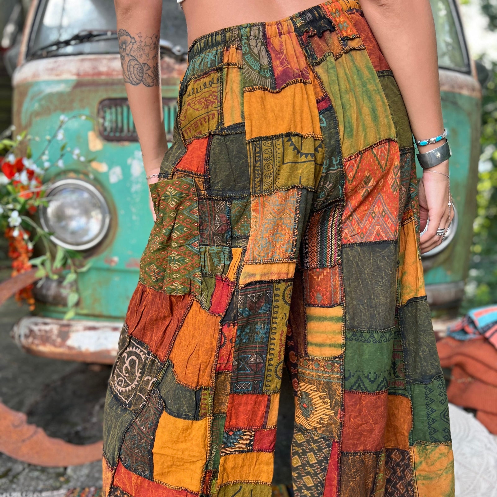 A woman wearing the Bohemian Patchwork Flare Wide Leg Pants in front of a vintage Volkswagen bus.