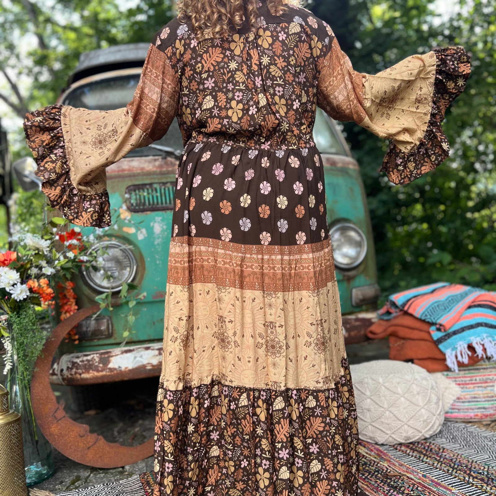 A woman wearing the Earthy Solstice Boho Bell Sleeve Maxi Dress in front of a vintage Volkswagen bus.