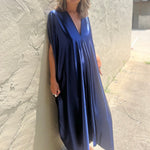 A woman wearing the Shadow Caftan with a pair of brown boots in front of a white building.