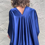 A woman wearing the Shadow Caftan in front of a white building.