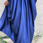 A woman wearing the Shadow Caftan in front of a white building.