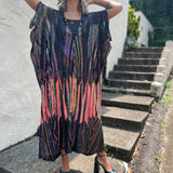 A woman wearing the Midnight Lotus Caftan with a black dress and heels.