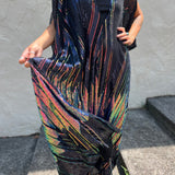A woman wearing the Midnight Lotus Caftan with a black dress and heels.