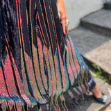 A woman wearing the Midnight Lotus Caftan with a black dress and heels.