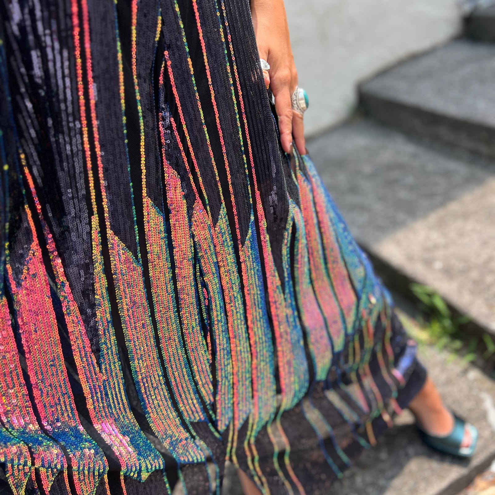 A woman wearing the Midnight Lotus Caftan with a black dress and heels.