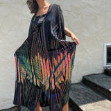 A woman wearing the Midnight Lotus Caftan with a black dress and heels.