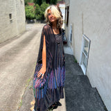 A woman wearing the Midnight Lotus Caftan with a black dress and heels.