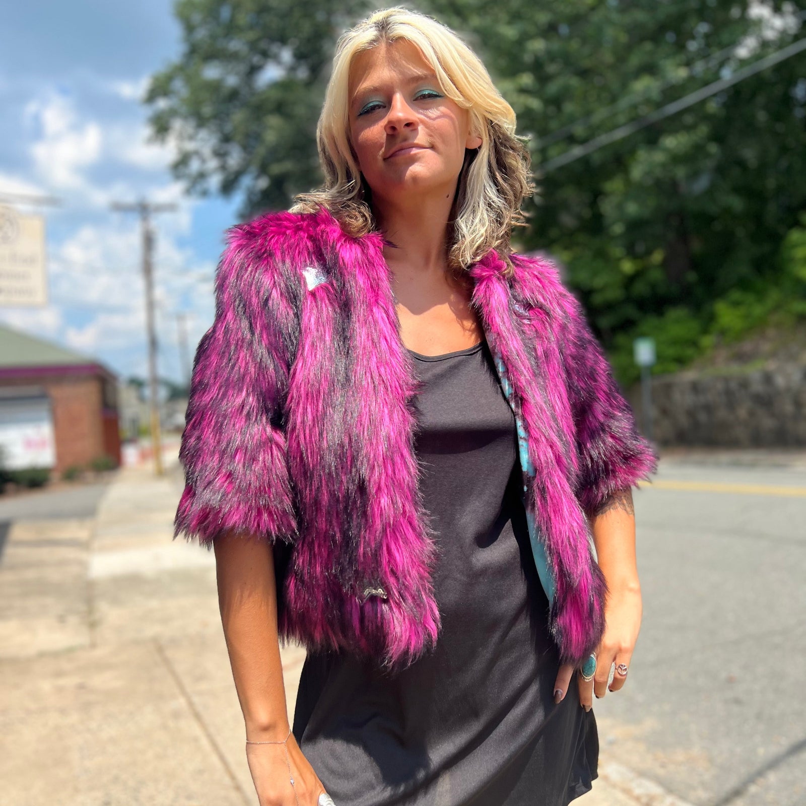 A woman wearing the Faux Fur Jacket in Monster Pink by Jennafer Grace with a black dress.