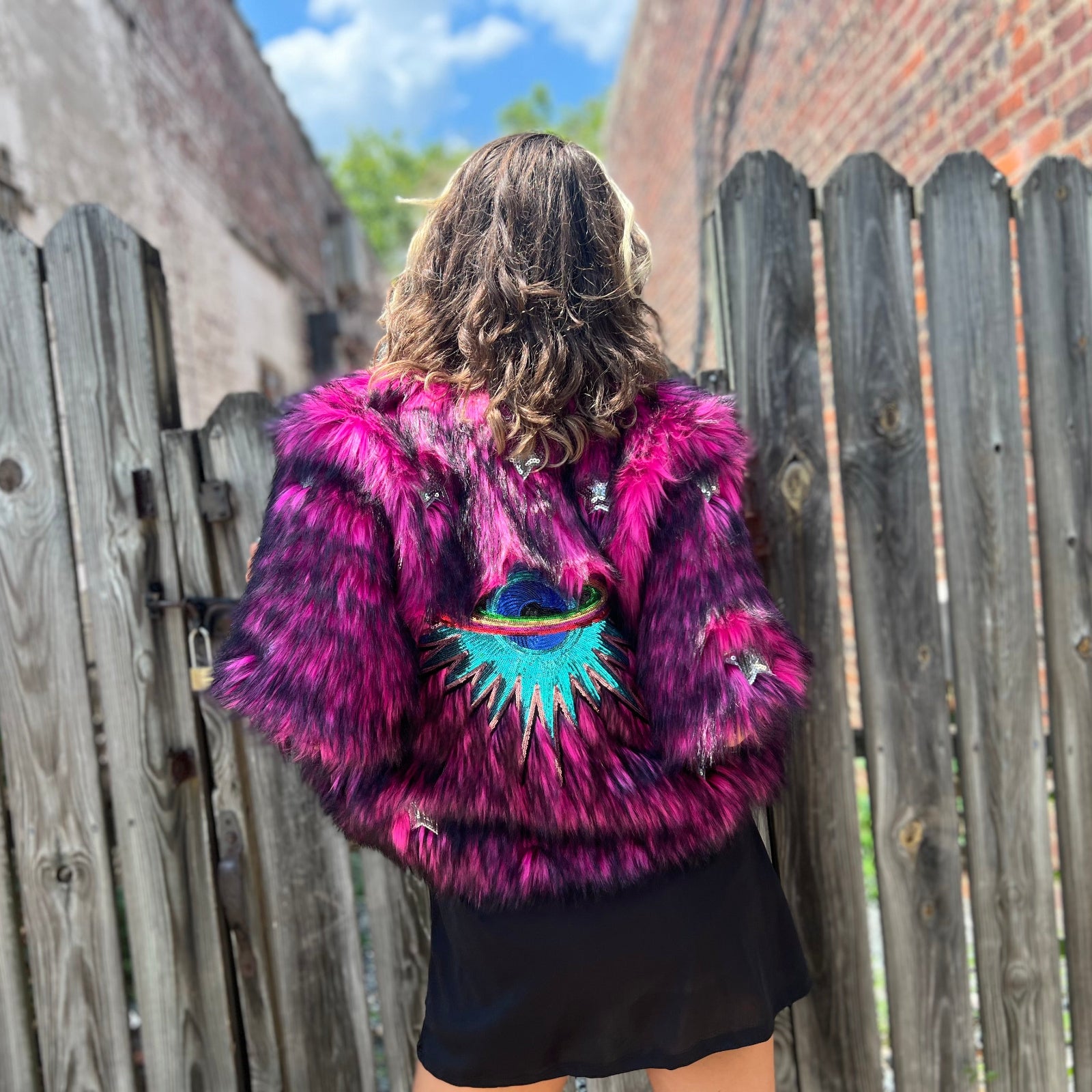 A woman wearing the Faux Fur Jacket in Monster Pink by Jennafer Grace with a black dress.