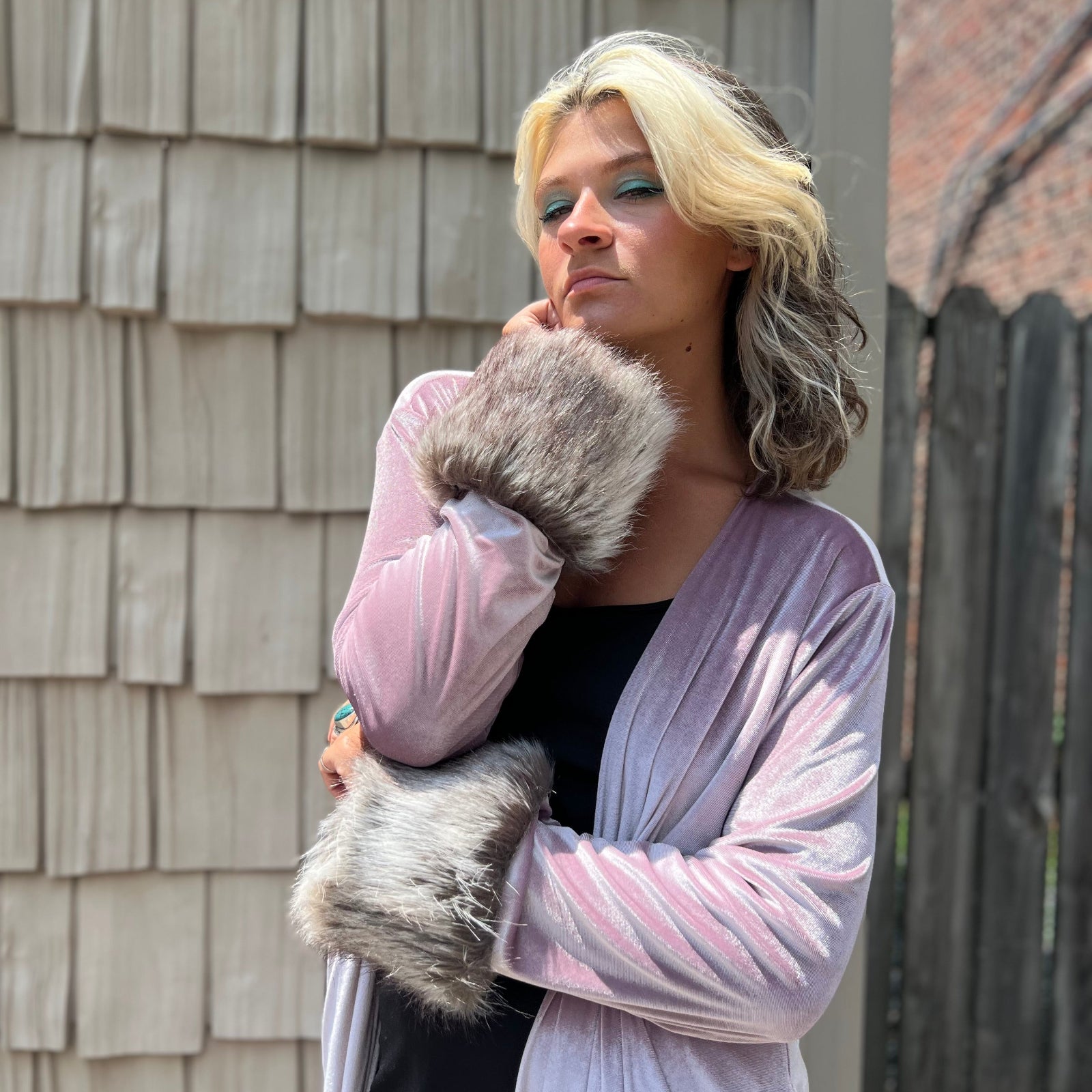 A woman wearing the Blush Velvet Faux Fur Jacket by Jennafer Grace with a black dress.