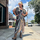 A woman wearing the Rainbow Rage Sequin Caftan with a black dress and brown boots.