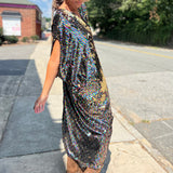 A woman wearing the Rainbow Rage Sequin Caftan with a black dress and brown boots.