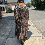 A woman wearing the Rainbow Rage Sequin Cocoon Jacket with a black dress and brown boots.