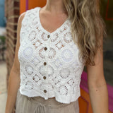 A woman wearing the white V-Neck Crochet Button Up Vest with beige linen pants.