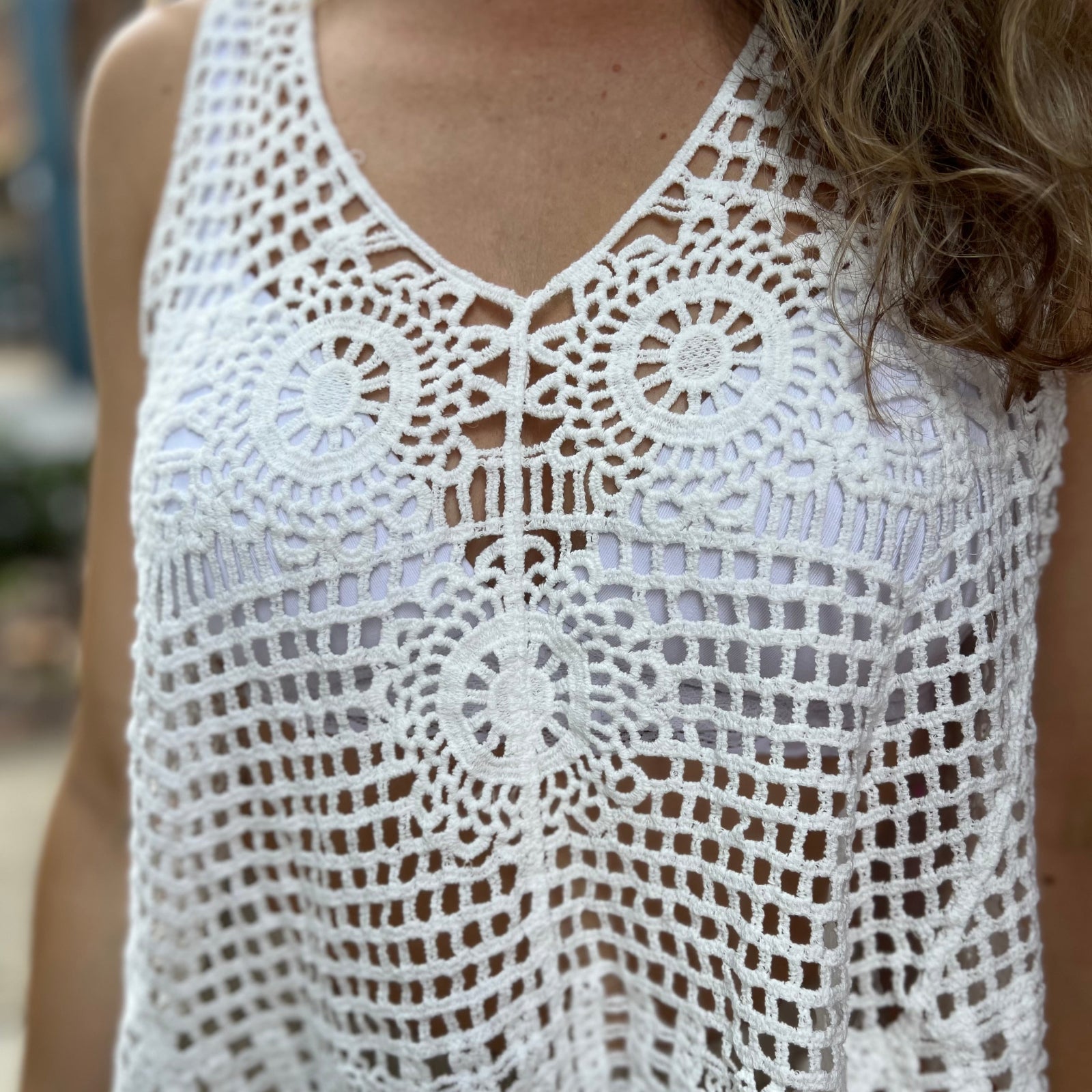 A woman wearing the white Bohemian Crochet Knit Sleeveless Tank with beige linen pants.