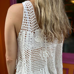 A woman wearing the white Bohemian Crochet Knit Sleeveless Tank with beige linen pants.