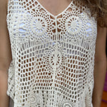 A woman wearing the white Bohemian Crochet Knit Sleeveless Tank with beige linen pants.