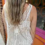 A woman wearing the beige Bohemian Crochet Knit Sleeveless Tank with beige linen pants.