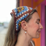 A woman wearing the Handmade Granny Square Crochet Headband around her head.