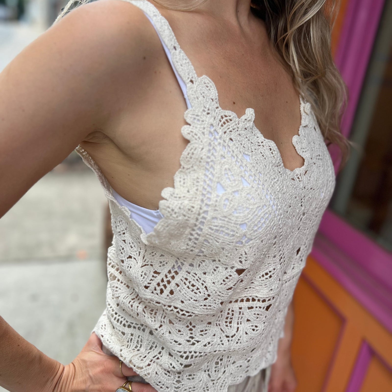 A woman wearing the beige Solid Color Crochet Lace Hollow Camisole Top with beige linen pants.