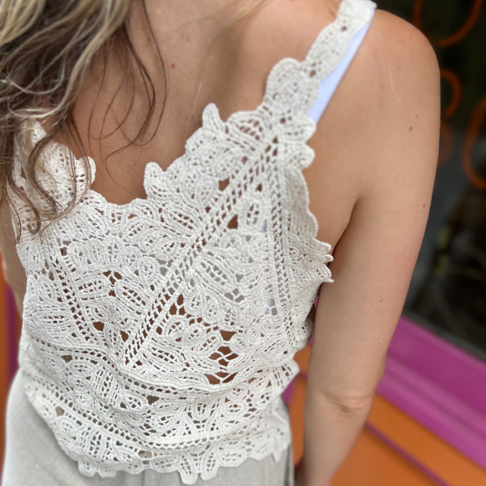 A woman wearing the beige Solid Color Crochet Lace Hollow Camisole Top with beige linen pants.
