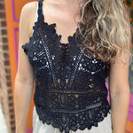 A woman wearing the black Solid Color Crochet Lace Hollow Camisole Top with beige linen pants.