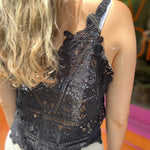 A woman wearing the black Solid Color Crochet Lace Hollow Camisole Top with beige linen pants.
