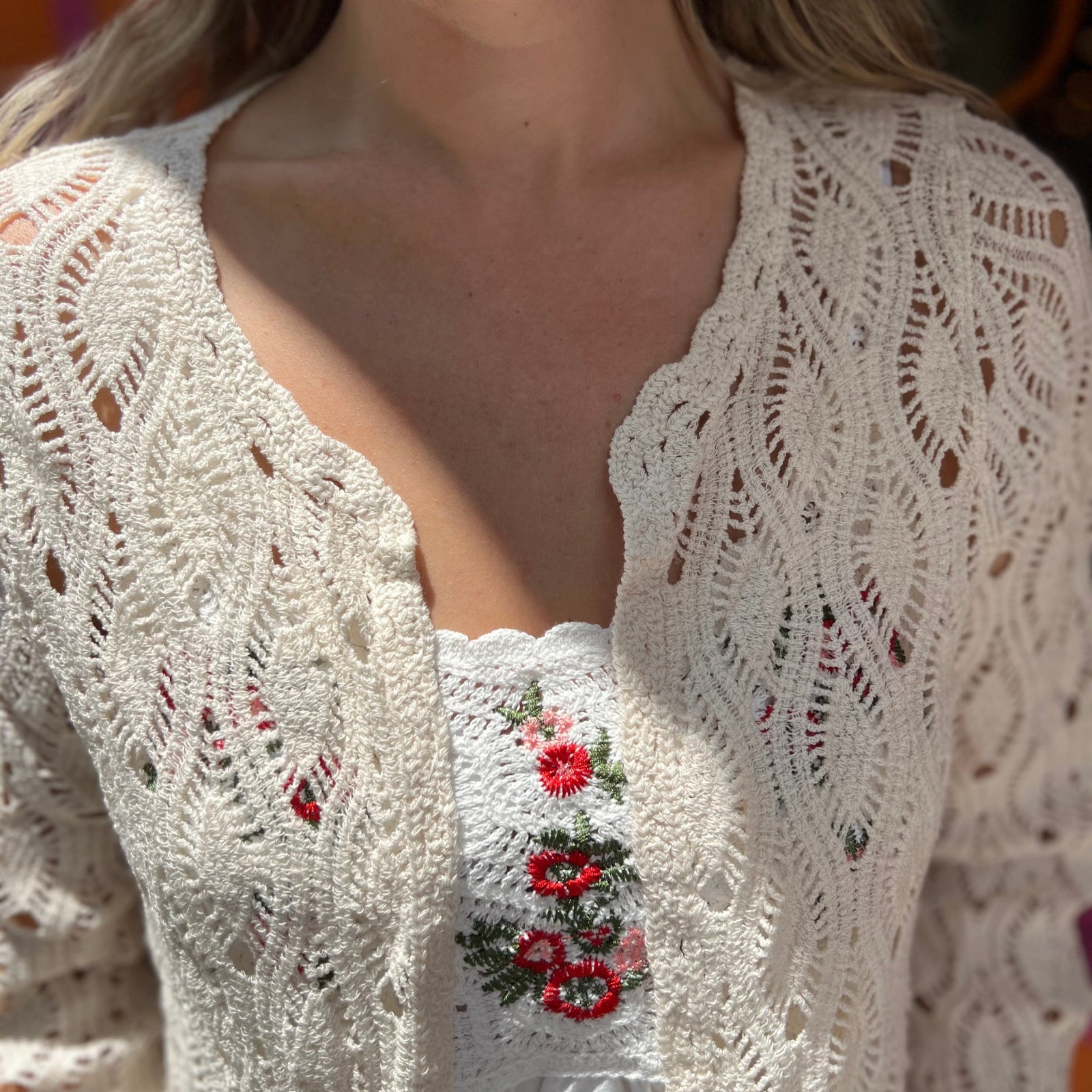 A woman wearing the Diamond Crochet Cardigan with a white dress.