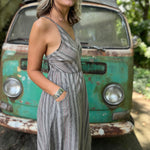 A woman wearing the Grey Striped Palazzo Cotton Jumpsuit in front of a vintage Volkswagen bus, showing off the side.
