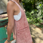 A woman wearing the Pink Garment Washed Cotton Denim Overall Dress in front of a vintage teal Volkswagen bus.