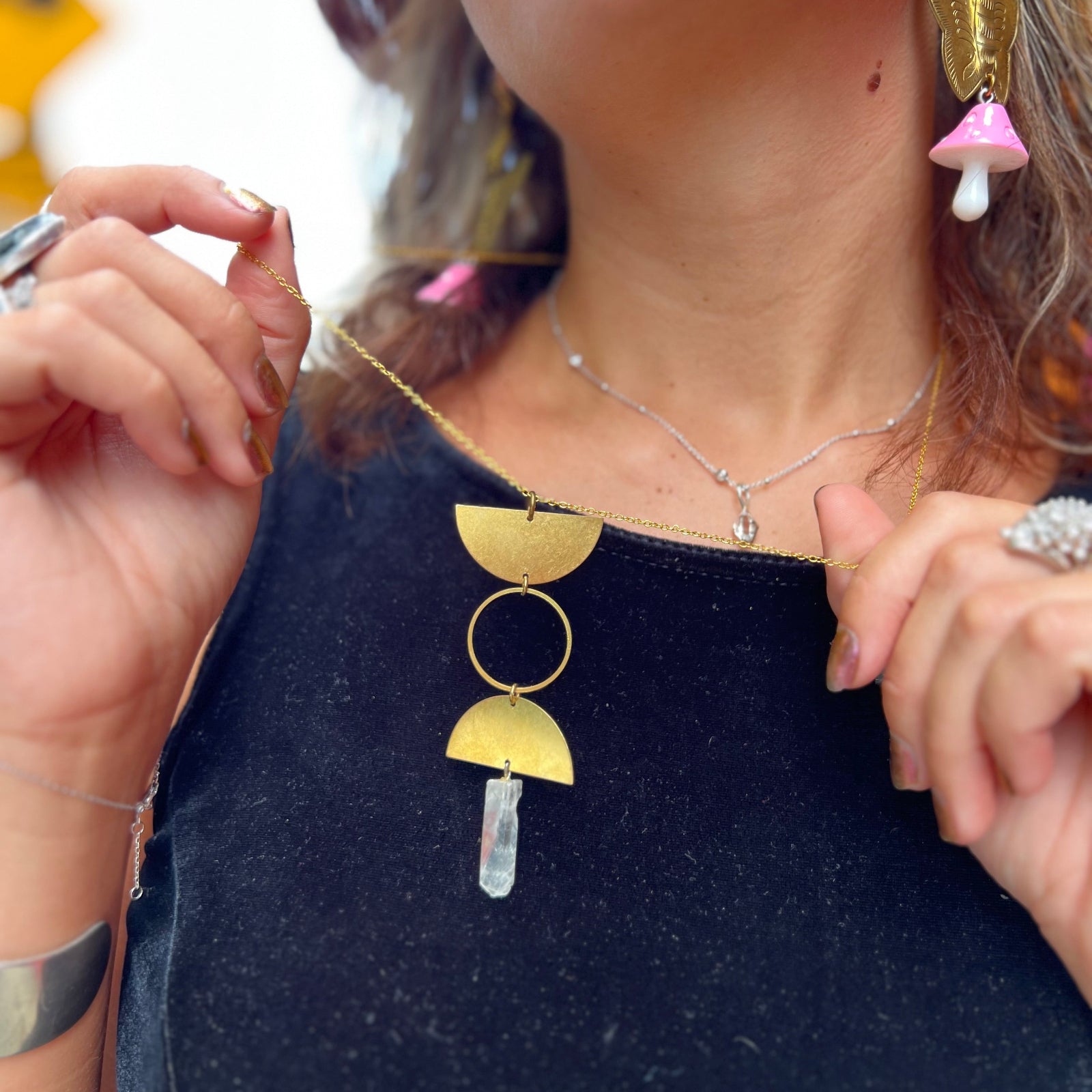 Someone wearing the Just a Phase Necklace with a black top and holding it out.