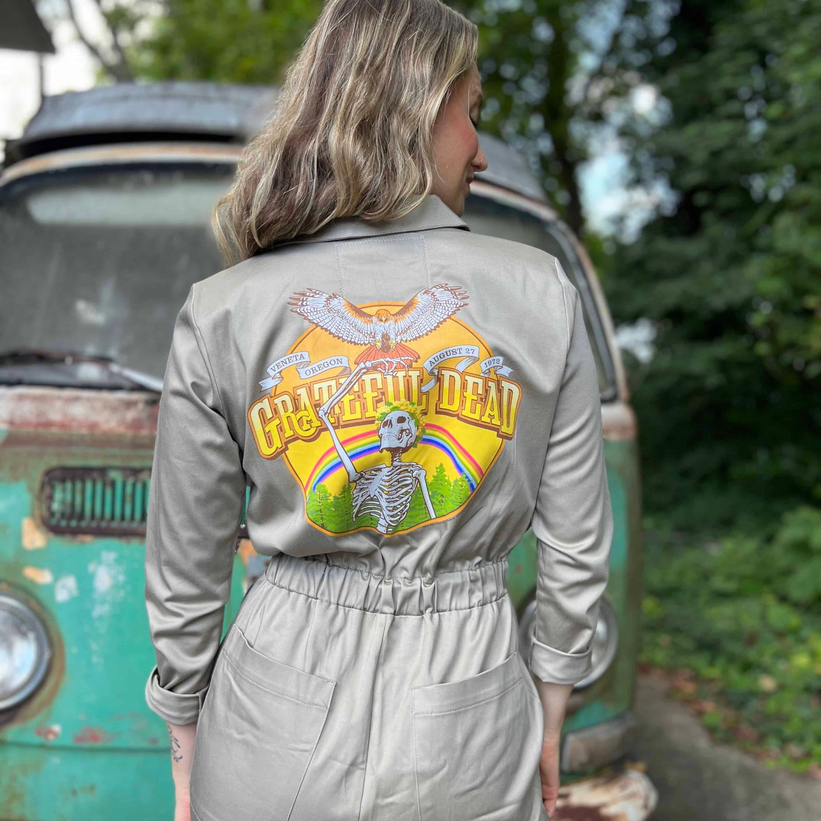 Person wearing a jumpsuit with Grateful Dead logo in front of a vintage van.
